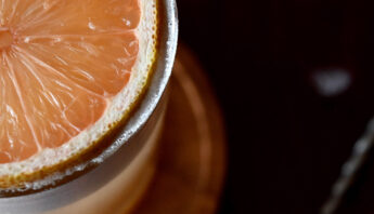 cocktail with a round slice of pink lemon as garnish