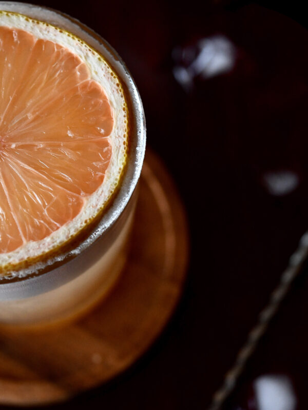 cocktail with a round slice of pink lemon as garnish