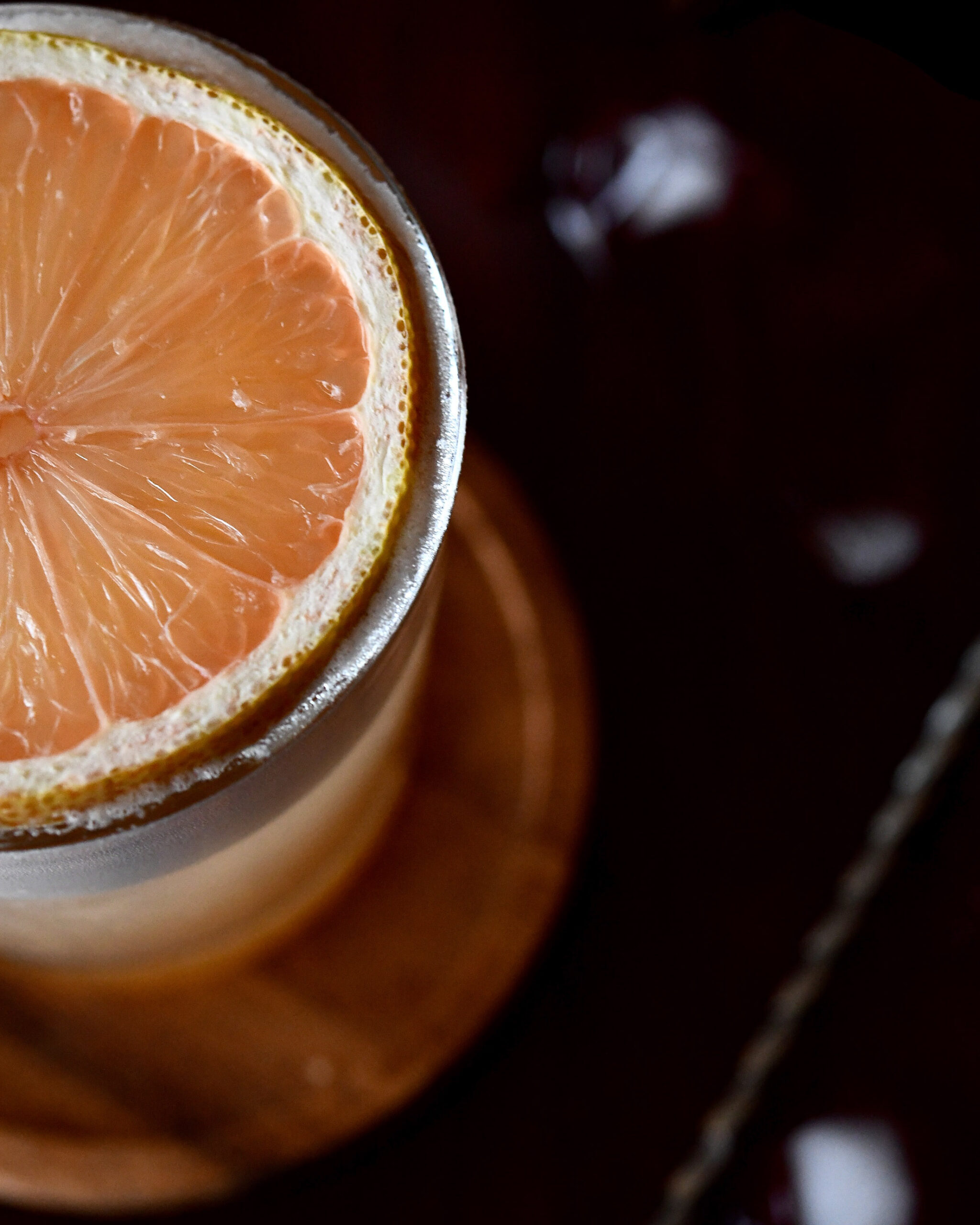 cocktail with a round slice of pink lemon as garnish